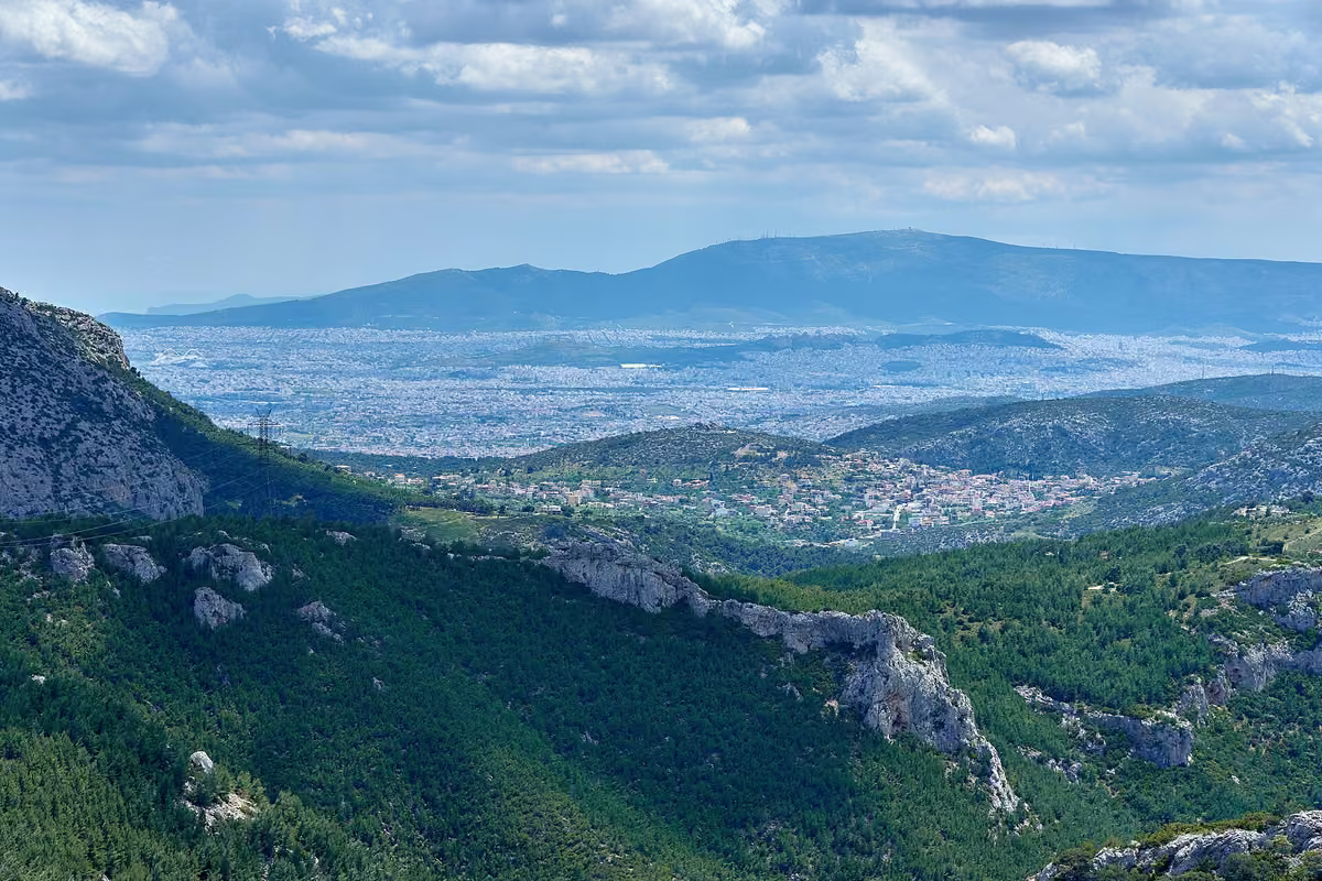 The wooded gorge below the Phyle fortress on western Parnitha, with Athens and Mount Hymettus on the horizon