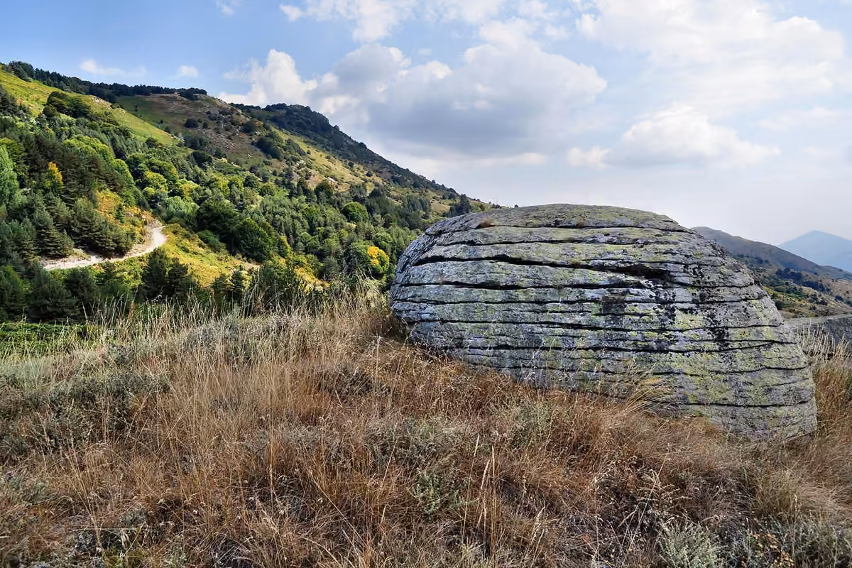 A large weathered boulder in a meadow on the green slopes above Ano Vrontou