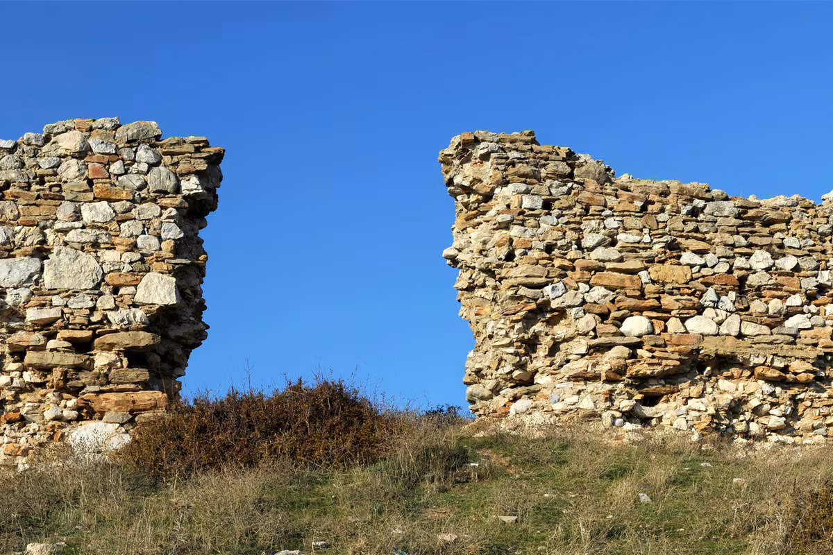 Two broken stone walls of the Byzantine castle against a blue sky