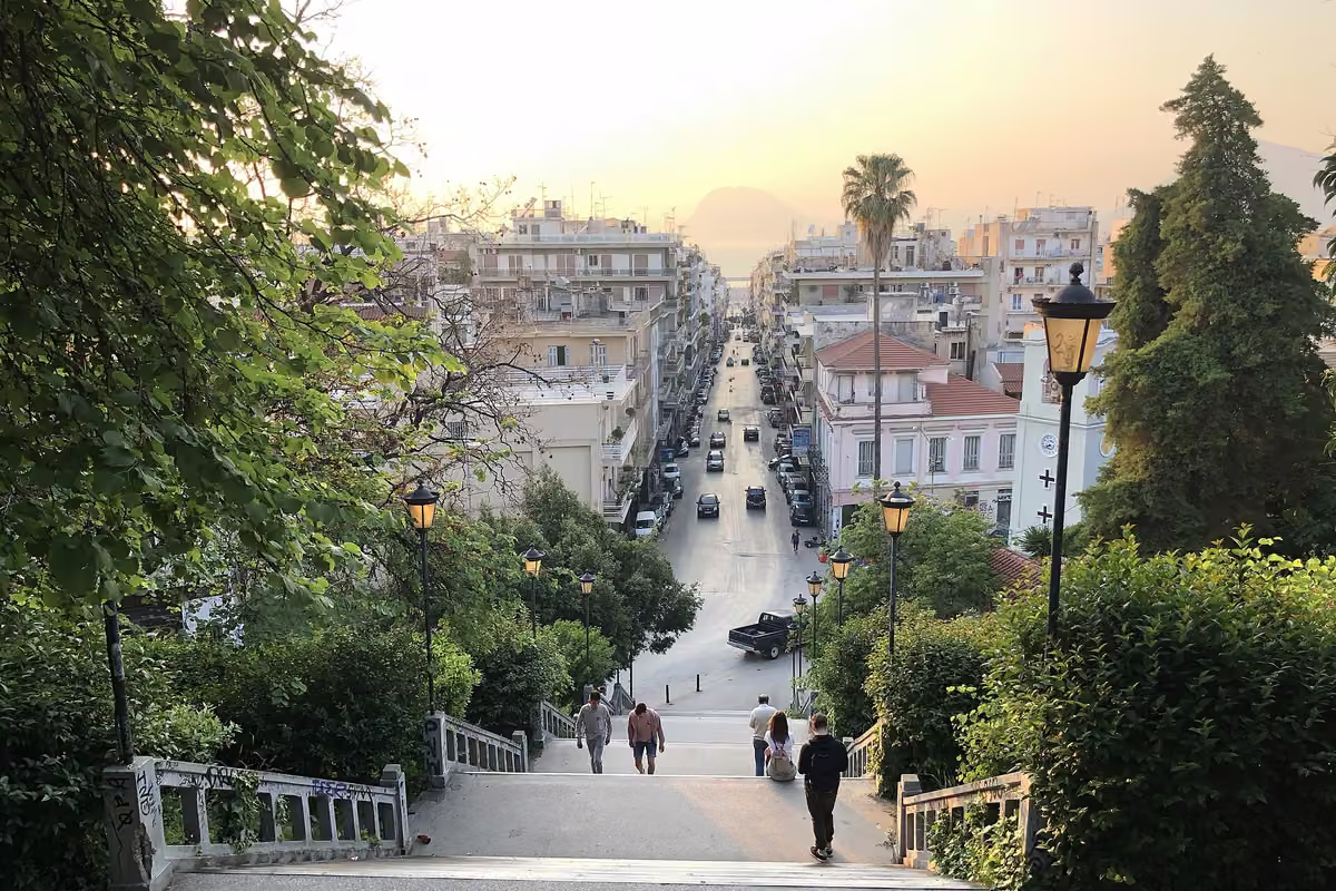 A street lined with trees and lamps running straight down to the sea at sunset