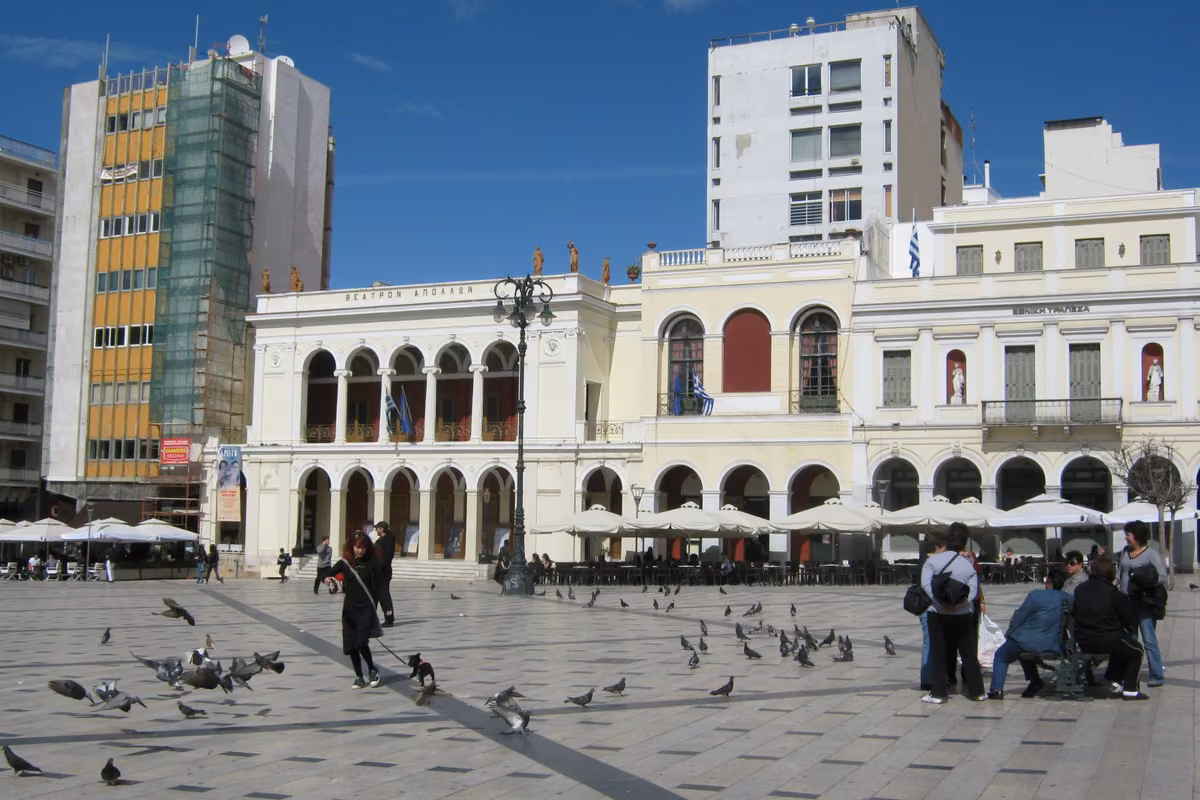 A wide paved square in front of an arcaded neoclassical theatre