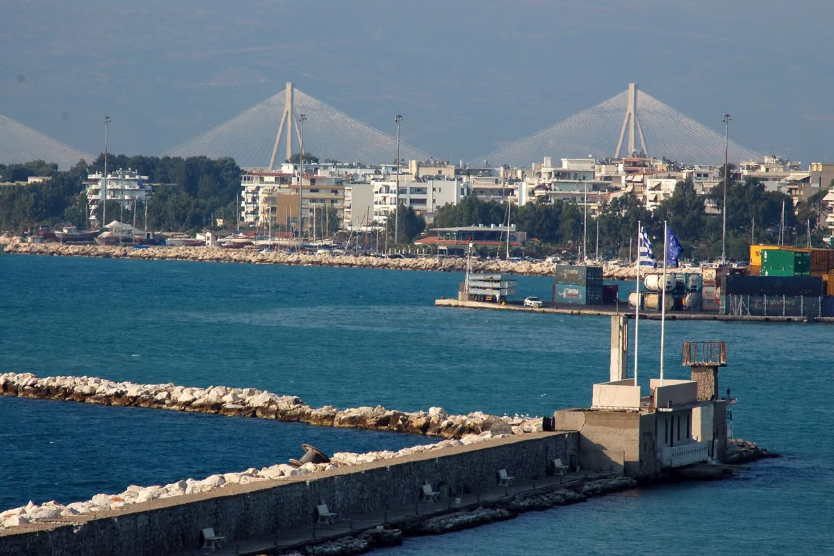 A harbour breakwater with a small lighthouse, the city and the cable-stayed bridge behind