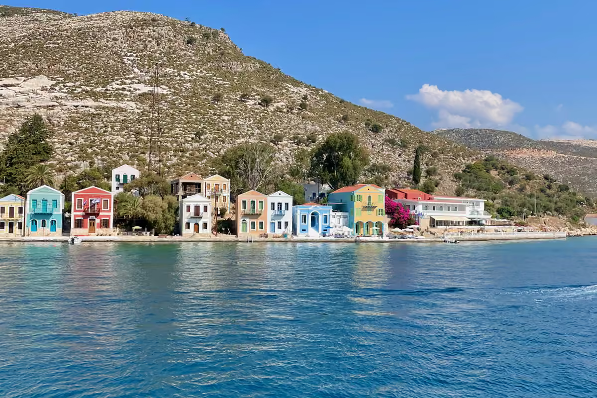 A row of brightly painted houses on the waterfront under a dry hillside